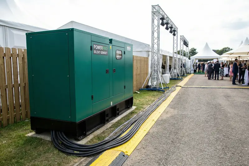 Gerador cabinado silencioso instalado discretamente nos bastidores de evento corporativo